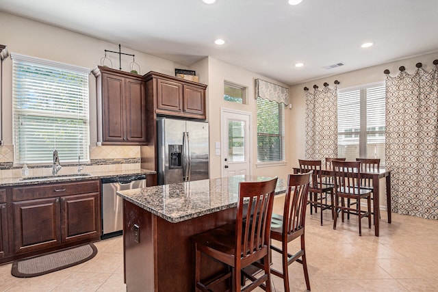 kitchen featuring a center island, stainless steel appliances, light stone countertops, and sink