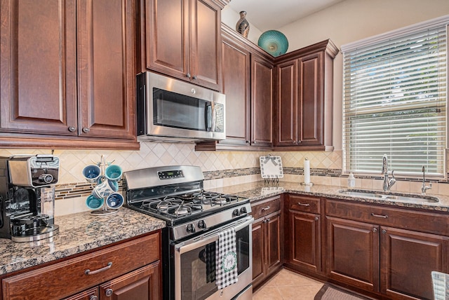 kitchen with stainless steel appliances, tasteful backsplash, sink, and light stone counters