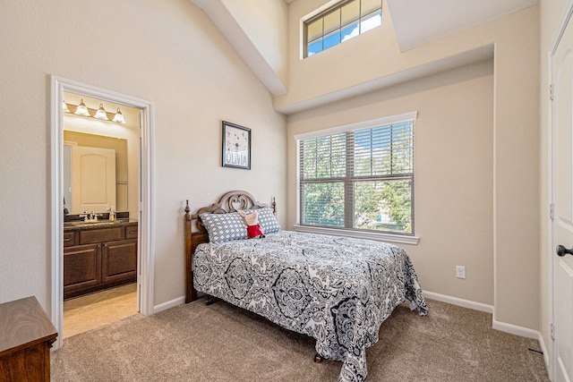 bedroom featuring connected bathroom, sink, light carpet, and a high ceiling