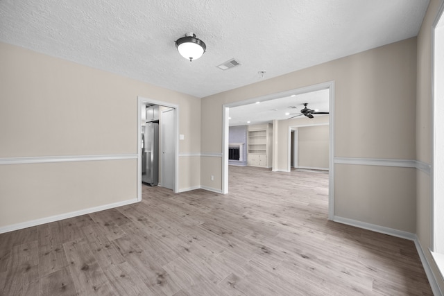 empty room featuring a textured ceiling, light hardwood / wood-style floors, and ceiling fan