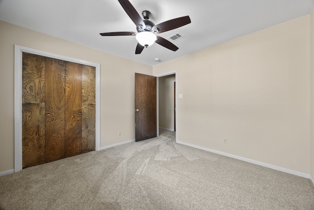 unfurnished bedroom featuring ceiling fan, light colored carpet, and a closet