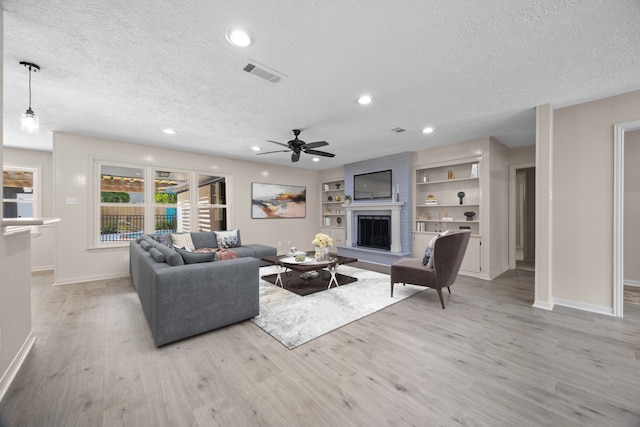 living room with a textured ceiling, ceiling fan, light hardwood / wood-style flooring, and built in features