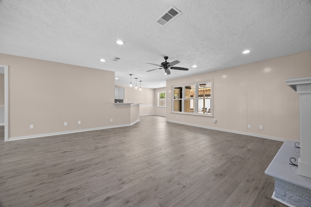 unfurnished living room with ceiling fan, a textured ceiling, and dark wood-type flooring