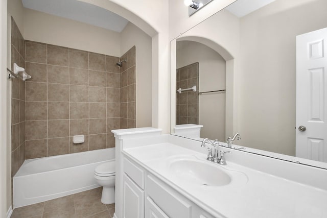 full bathroom with tile patterned floors, vanity, tiled shower / bath combo, and toilet