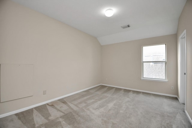 spare room with light colored carpet and lofted ceiling