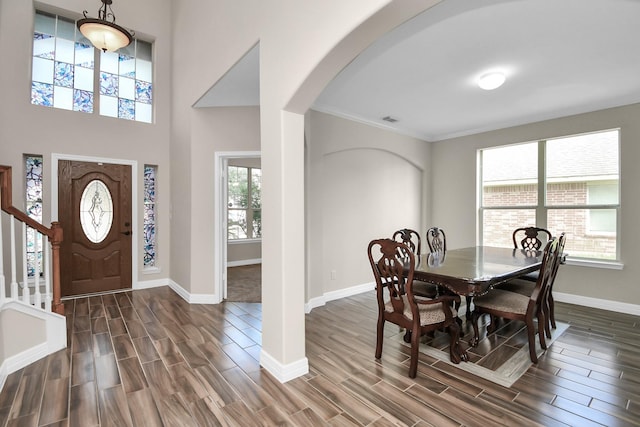 dining area with ornamental molding, a towering ceiling, and dark wood-type flooring