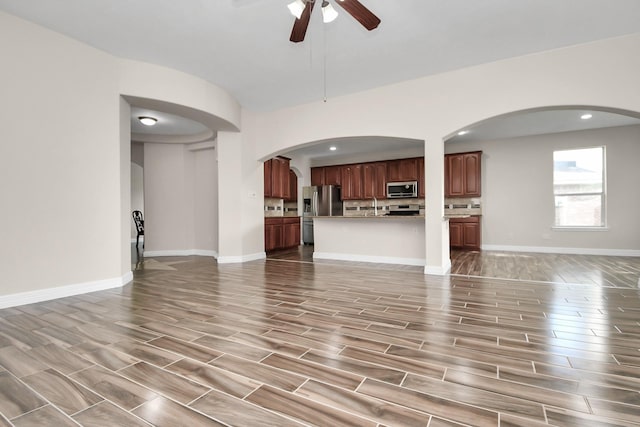 unfurnished living room featuring ceiling fan, wood-type flooring, and sink