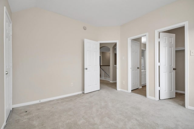 unfurnished bedroom featuring a walk in closet, light carpet, and a closet