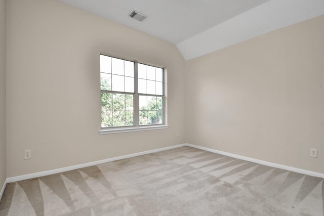 spare room featuring light carpet and lofted ceiling