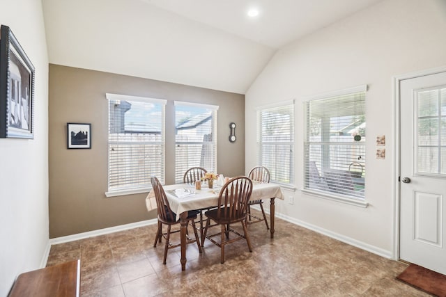 tiled dining room featuring a healthy amount of sunlight and vaulted ceiling