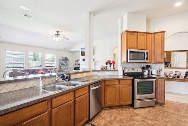 kitchen featuring sink, vaulted ceiling, decorative backsplash, stainless steel appliances, and ceiling fan