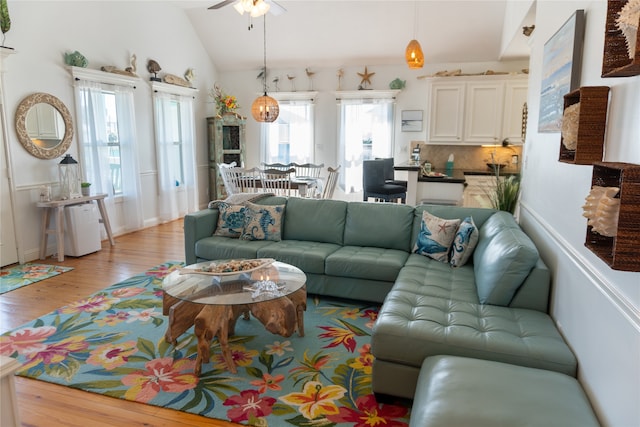 living room with light hardwood / wood-style flooring, vaulted ceiling, and ceiling fan