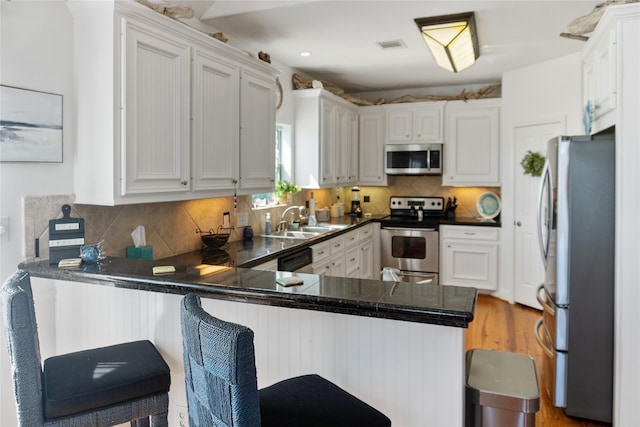 kitchen featuring white cabinets, stainless steel appliances, kitchen peninsula, and a kitchen breakfast bar