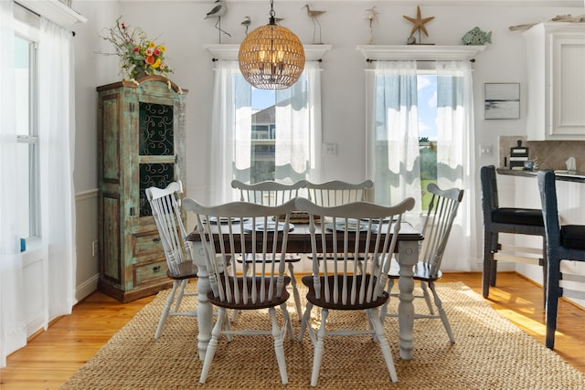 dining room with a wealth of natural light, light wood-type flooring, and an inviting chandelier