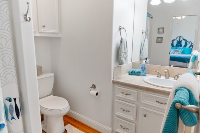 bathroom with toilet, vanity, and wood-type flooring