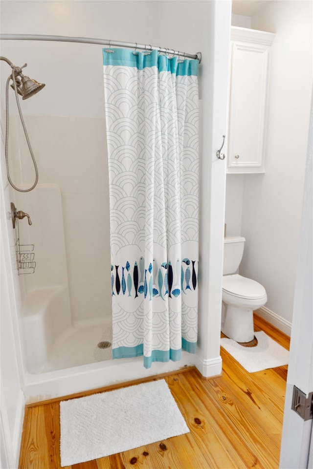 bathroom featuring toilet, wood-type flooring, and a shower with shower curtain