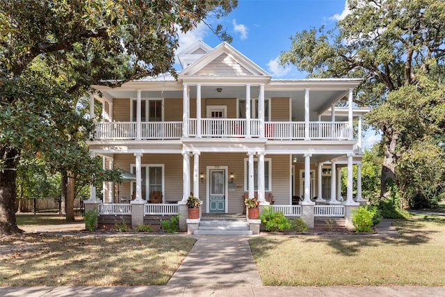 greek revival house featuring a balcony, a front lawn, and covered porch