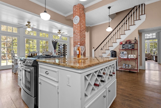 kitchen with white cabinetry, stainless steel stove, decorative columns, and hanging light fixtures