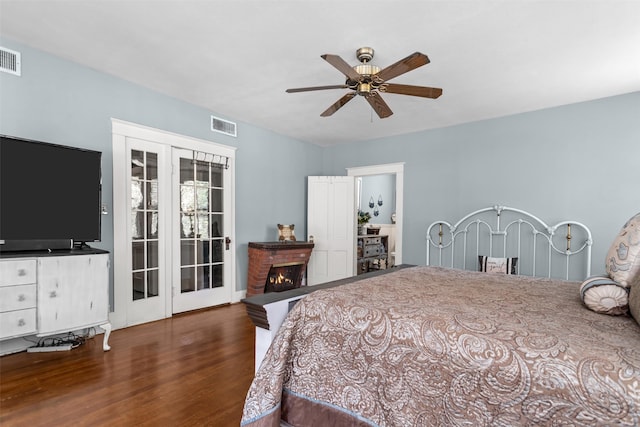 bedroom with ceiling fan, a fireplace, and dark wood-type flooring