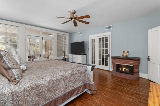 bedroom with dark hardwood / wood-style floors, access to outside, a brick fireplace, ceiling fan, and french doors