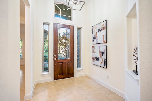 foyer with light tile patterned floors, a high ceiling, and baseboards