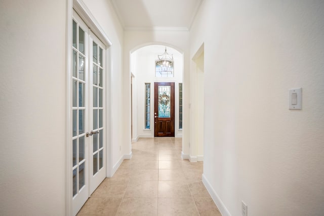 doorway featuring ornamental molding, an inviting chandelier, french doors, and light tile patterned floors