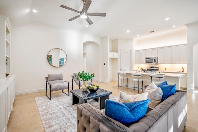 living room featuring arched walkways, baseboards, ceiling fan, ornamental molding, and recessed lighting