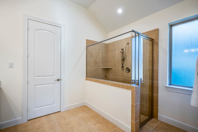 bathroom with a stall shower, baseboards, vaulted ceiling, and tile patterned floors