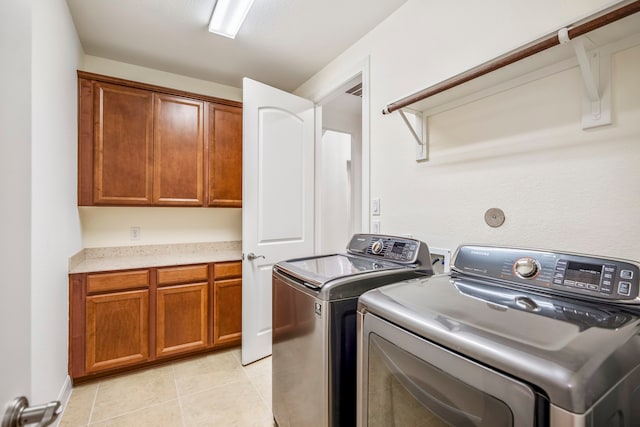 laundry room featuring washer and clothes dryer, cabinets, and light tile patterned floors