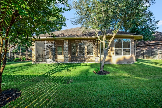 back of property with a sunroom and a yard