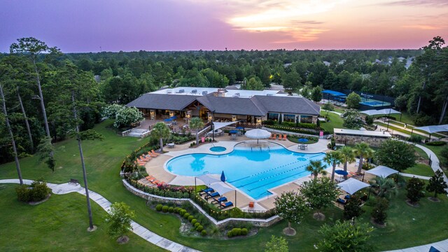 pool at dusk featuring a yard and a patio