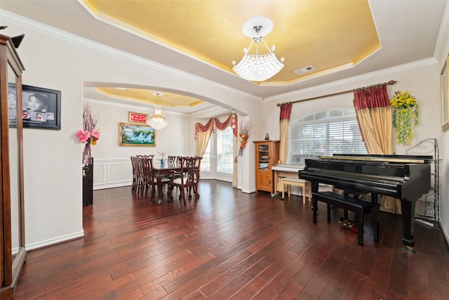 interior space featuring a raised ceiling, ornamental molding, dark hardwood / wood-style floors, and a notable chandelier