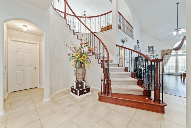 stairs with high vaulted ceiling, tile patterned flooring, and ceiling fan