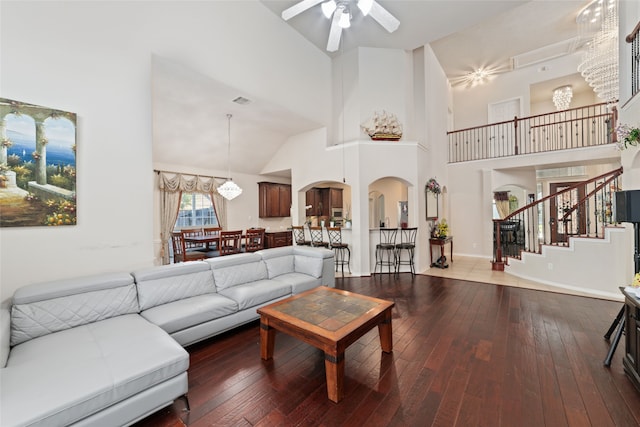 living room with high vaulted ceiling, ceiling fan with notable chandelier, and hardwood / wood-style flooring