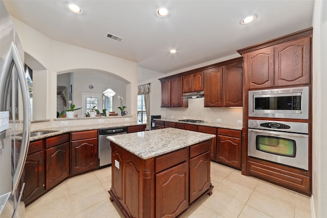 kitchen featuring light tile patterned floors, kitchen peninsula, a kitchen island, stainless steel appliances, and light stone countertops