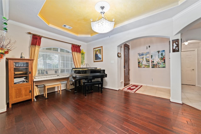 miscellaneous room with an inviting chandelier, a raised ceiling, dark hardwood / wood-style floors, and ornamental molding