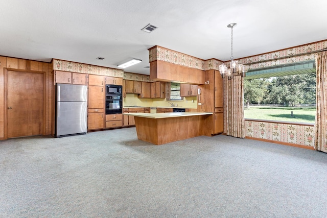 kitchen with an inviting chandelier, kitchen peninsula, light colored carpet, decorative light fixtures, and black appliances