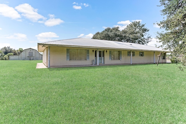 rear view of property featuring a yard and an outdoor structure