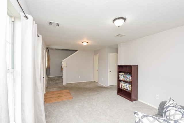 sitting room with a textured ceiling and light colored carpet