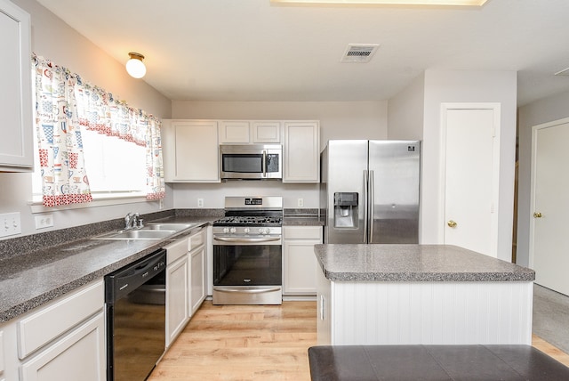 kitchen with appliances with stainless steel finishes, a center island, sink, and white cabinets