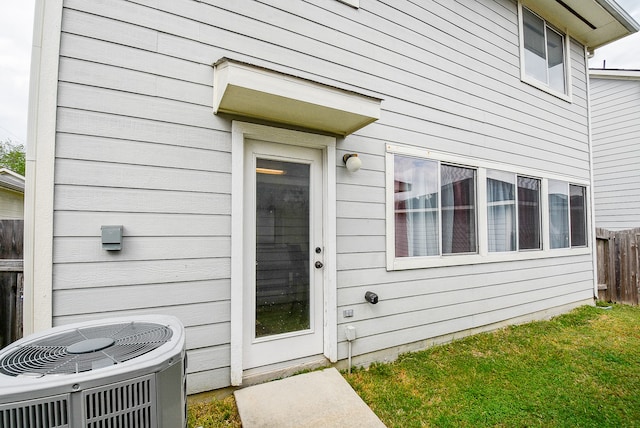 property entrance with cooling unit and a lawn