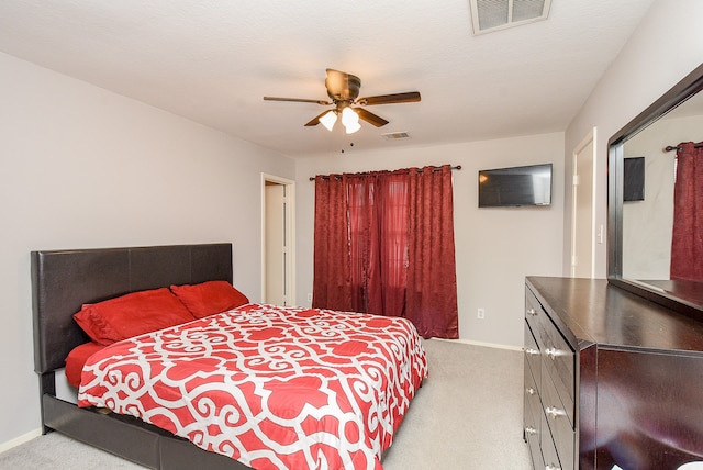 bedroom featuring light carpet, ceiling fan, and a textured ceiling