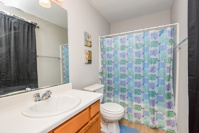 bathroom with a shower with shower curtain, hardwood / wood-style flooring, vanity, and toilet