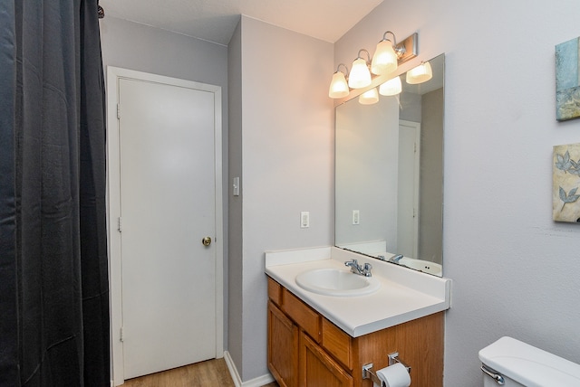 bathroom with wood-type flooring, vanity, and toilet