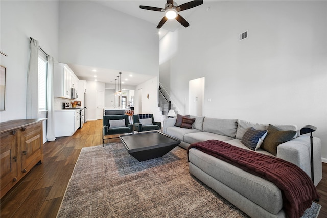 living room featuring a towering ceiling, ceiling fan, and dark hardwood / wood-style floors