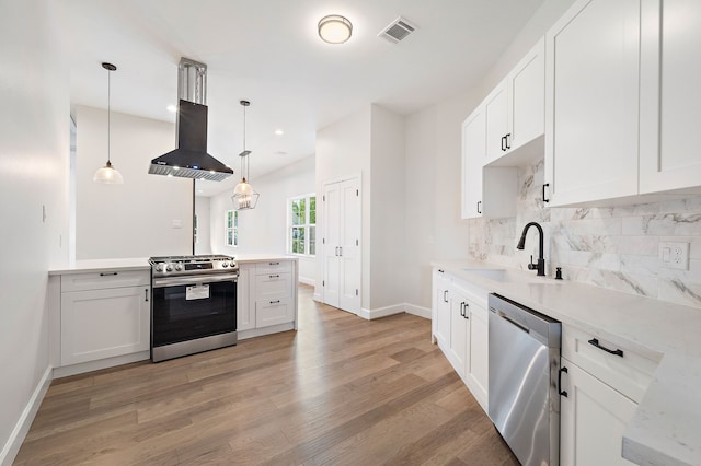 kitchen with decorative light fixtures, island exhaust hood, appliances with stainless steel finishes, and white cabinetry