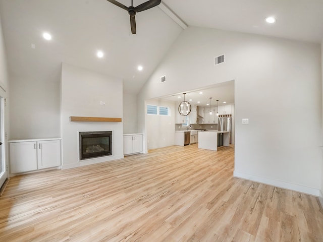 unfurnished living room featuring high vaulted ceiling, light wood-type flooring, beam ceiling, and ceiling fan