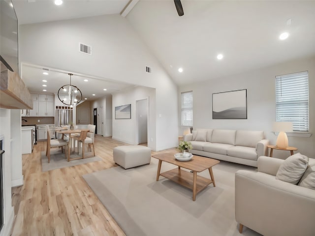 living room with light hardwood / wood-style flooring, beam ceiling, a chandelier, and high vaulted ceiling