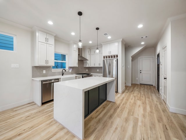 kitchen featuring hanging light fixtures, white cabinets, a kitchen island, stainless steel appliances, and light wood-type flooring