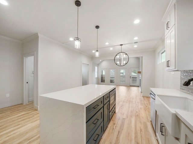 kitchen featuring white cabinets, light hardwood / wood-style flooring, pendant lighting, and a center island